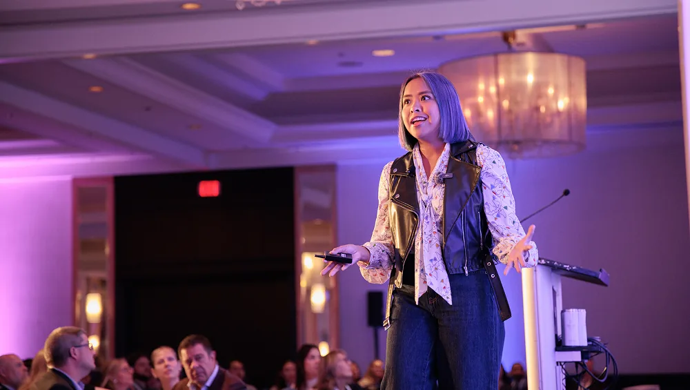 Erika Casupanan speaking on a ballroom stage